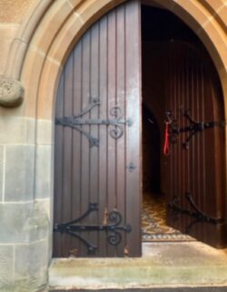 Pair of dark-stained ornate timber double doors featuring gothic arch design and decorative hardware, in the Victorian heritage style, crafted by Marrickville Joinery.