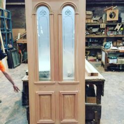 Pair of heritage entrance doors with a decorative arched fanlight window above and ornate glass inserts — a classic Federation-era design.