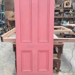 A painted pink two-panel timber door, representative of a simple heritage interior design.