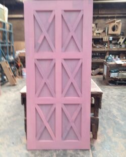 Multiple sections of pink painted decorative X-cross gate or door panels, a classic heritage design element.