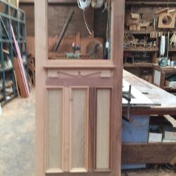 A door featuring louvre panel sections in the lower half, pink painted for a heritage residential exterior.