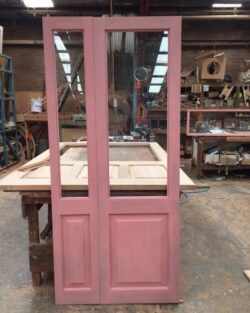Double pink painted heritage timber doors with multiple panels, photographed in the workshop prior to delivery.