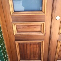 A solid timber door with richly detailed raised panel mouldings in a warm stained finish, demonstrating high-quality heritage craftsmanship.