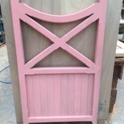 Pink painted heritage door featuring a decorative X-cross motif in the upper panel — a classic detail for heritage gates and entrances.