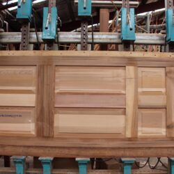 Workshop scene showing multiple timber door and window frames at various stages of production.