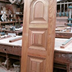 A richly detailed heritage solid timber door featuring a traditional raised panel design, stained to a warm finish.