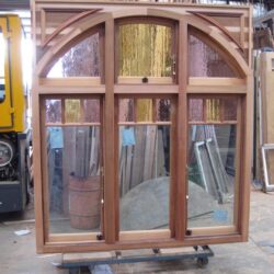 Large heritage triple-opening arched door unit in natural timber, with three panels beneath a wide decorative arch.