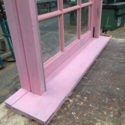 Close-up of pink painted timber door frame and surround, showing the moulded profile of heritage door joinery.