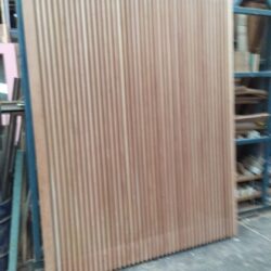 Vertical lengths of timber boards and mouldings stored in the workshop, ready for use in heritage joinery projects. Timber Planks and Mouldings in Workshop