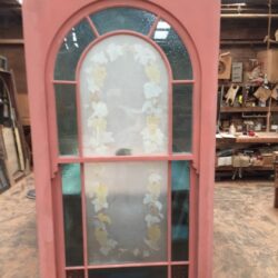 Looking through a heritage arched opening or doorway, revealing decorative leadlight or glass detail within.