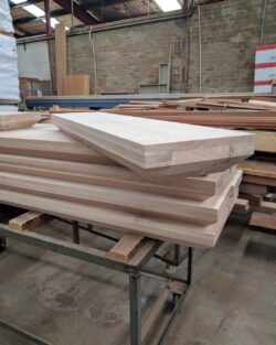 Sheets of MDF or engineered timber panels stacked on the workshop floor, used as material for joinery production. Stack of Timber Panels