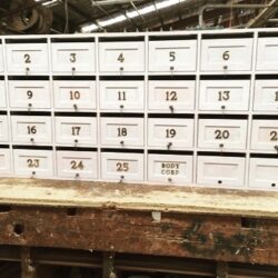 Wall-mounted shelving unit with numbered pigeon-hole compartments, used for organised storage of small parts and fittings in the workshop. Numbered Storage Compartments