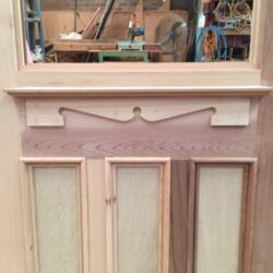Timber heritage doors showing an elaborate carved or moulded header and pediment detail above the door opening.
