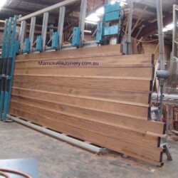 Offcuts and lengths of various timber pieces stacked in the workshop, showing the range of materials used in heritage joinery. Stacked Timber Offcuts