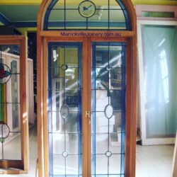 Heritage entrance door in dark teal/green with a semi-circular arched leadlight fanlight above, a classic Victorian residential feature.