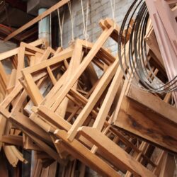 Workshop storage area with timber window and door frames leaning against the walls, typical of an active heritage joinery production space.