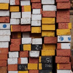 Stack of colourful brick and tile material samples in varying shades of red, orange and yellow, used for heritage restoration matching.