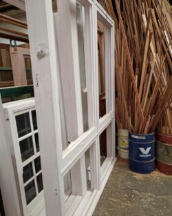 Workshop interior scene featuring pink painted window or door frames at various stages of construction.