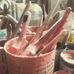 Collection of woodturning tools — chisels and gouges — stored in a timber pot, used for turning decorative elements like balusters and newel posts.