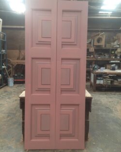 Pink painted six-panel heritage door showing the traditional raised panel configuration used in period home restorations.