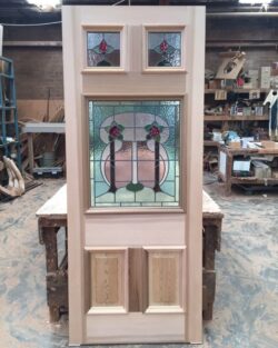 Heritage door panel featuring decorative stained glass insert with an ornate pattern, combining traditional craftsmanship with art glass.