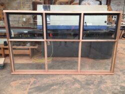 Workshop interior showing door and window frames at various stages of production, capturing the active joinery environment.