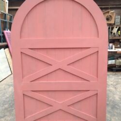 Pink painted stable or barn-style door featuring an arched top, a charming heritage-style design for residential or garden use.